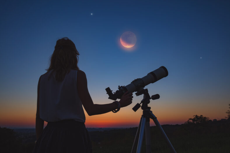 Girl looking at lunar eclipse through a telescope. My astronomy work.