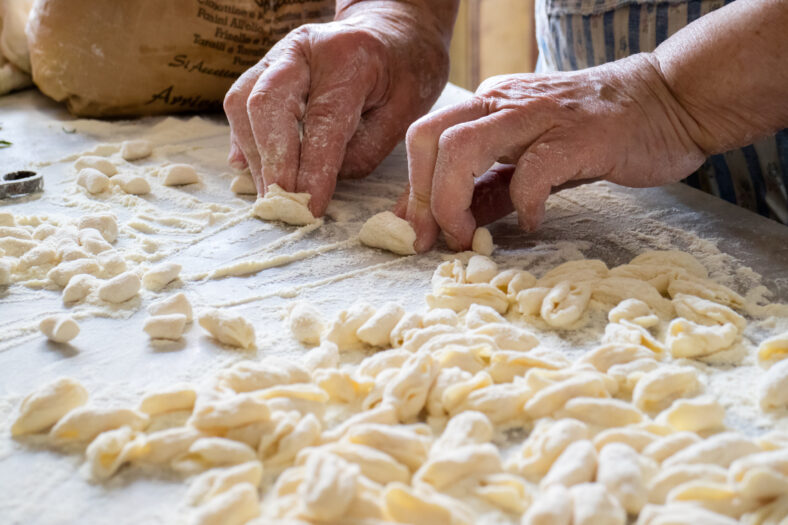 Hands of Italian woman making traditional fresh homemade pasta on a marble table