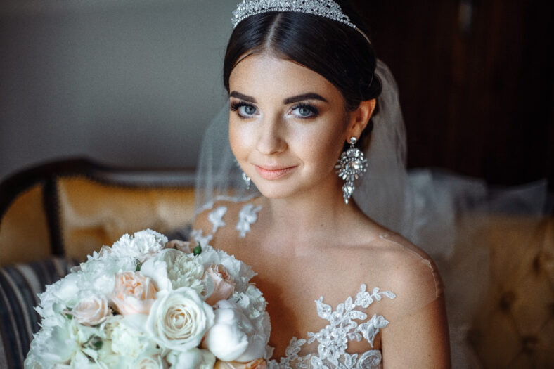 young beautiful bride in a luxurious wedding dress near the window with flowers