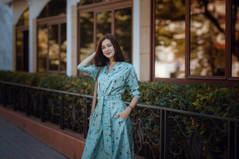 Fashion portrait of young stylish woman walking on the street, wearing cute trendy outfit, beautiful girl in a blue dress smiling enjoy her weekends.