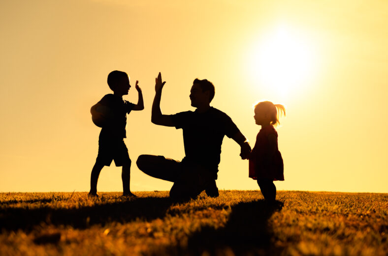 Father interacting playing outdoors with his children giving high five. Parenting and fatherhood concept.