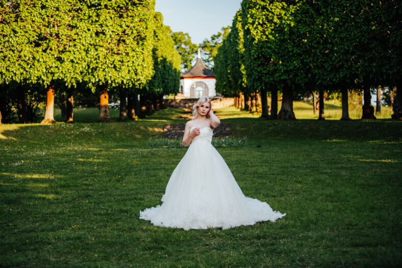 beautiful, blond bride standing in the park with a big, white dress