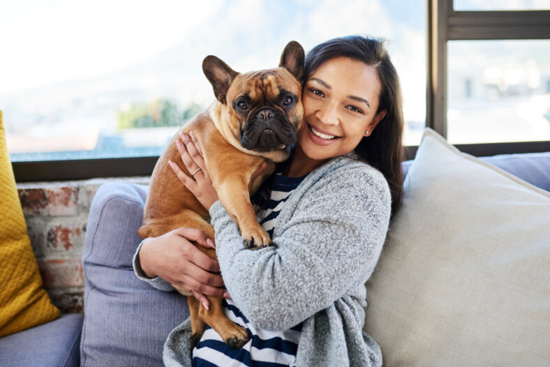 Portrait of a young woman relaxing with her dog at home.