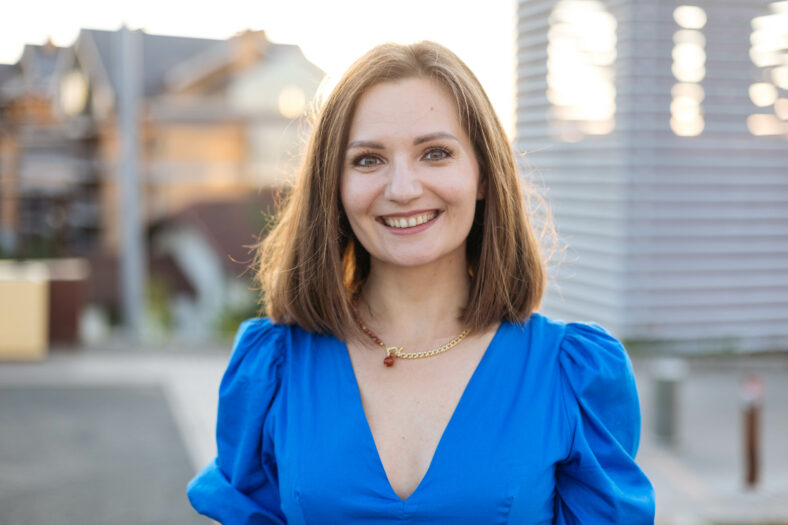 Portrait of a young happy woman on the background of a modern city, looking at the camera, smiling.