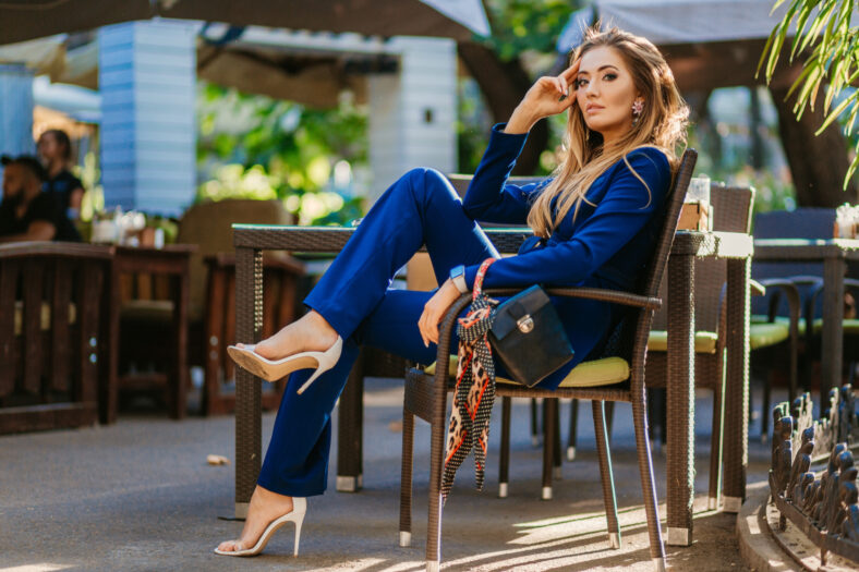 business woman wearing blue suit sitting in summer cafe, rich luxury style, long legs in high heeled shoes