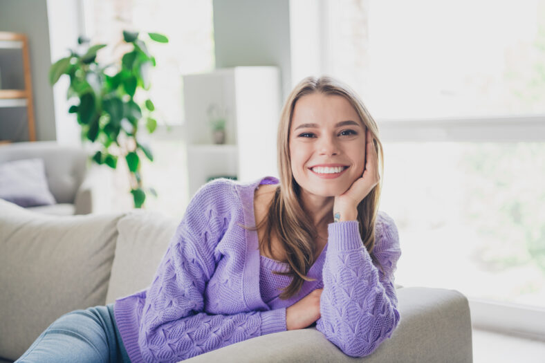 Photo of attractive young woman sit couch dreamy have rest dressed purple outfit cozy day light home interior living room.