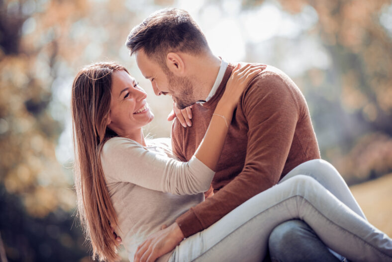 Feliz joven pareja divirtiéndose al aire libre y sonriendo.