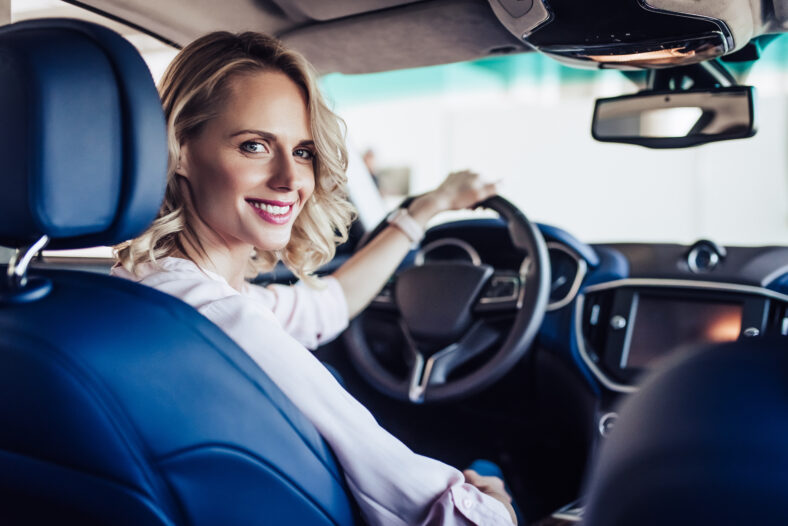 portrait of young smiling woman sitting in the car and looking at the camera