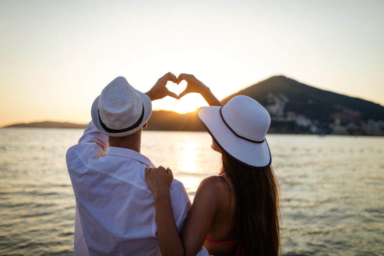 Happy young couple in love walking on beach on honeymoon vacation