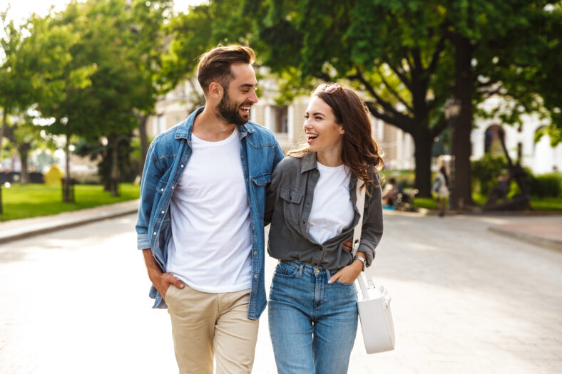 Hermosa joven pareja enamorada caminando al aire libre en la calle de la ciudad, abrazando