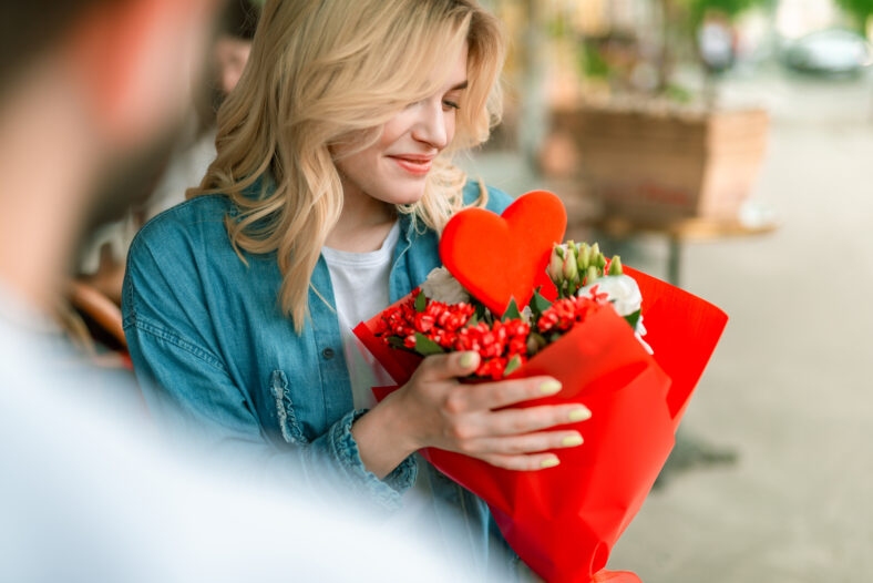 Cropped of smiling woman looking at bouquet of flowers from beloved man