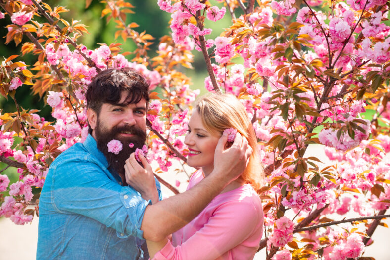 Pareja con una cita en Spring Blooming Park en un día de primavera con hermosas flores de cerezo en el fondo. Pareja de pascua