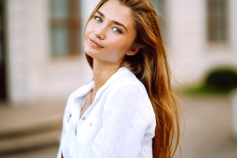 Portrait of young beautiful girl smiling looking at camera. Beautiful girl posing in the park. Summer and vacation concept