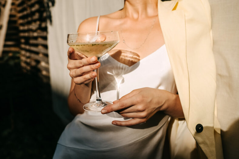 Luxurious woman wearing a white dress, holding a coupe with cham