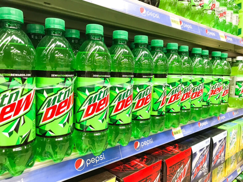 Bottles of Mountain Dew soft drink stand on a shelf of a supermarket.