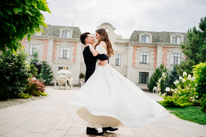 beautiful newlyweds dancing and whirling against the background of a light building. The bride and groom hug gently. first meeting before the wedding ceremony. walk in outdoor.