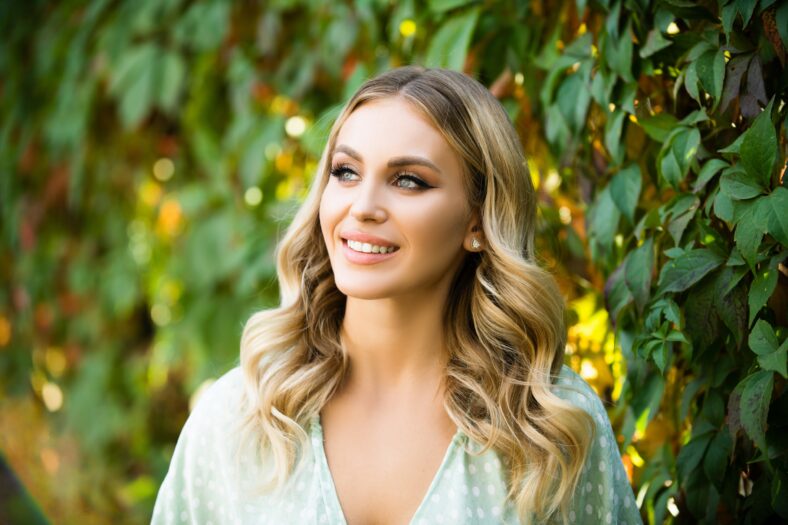 Retrato de una mujer joven, cara de cerca de una mujer hermosa en el parque al aire libre. Mujer con sonrisa romántica. Modelo femenina alegre