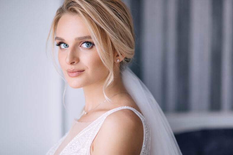 beautiful bride with blonde hair in elegant wedding dress posing in the room on wedding morning